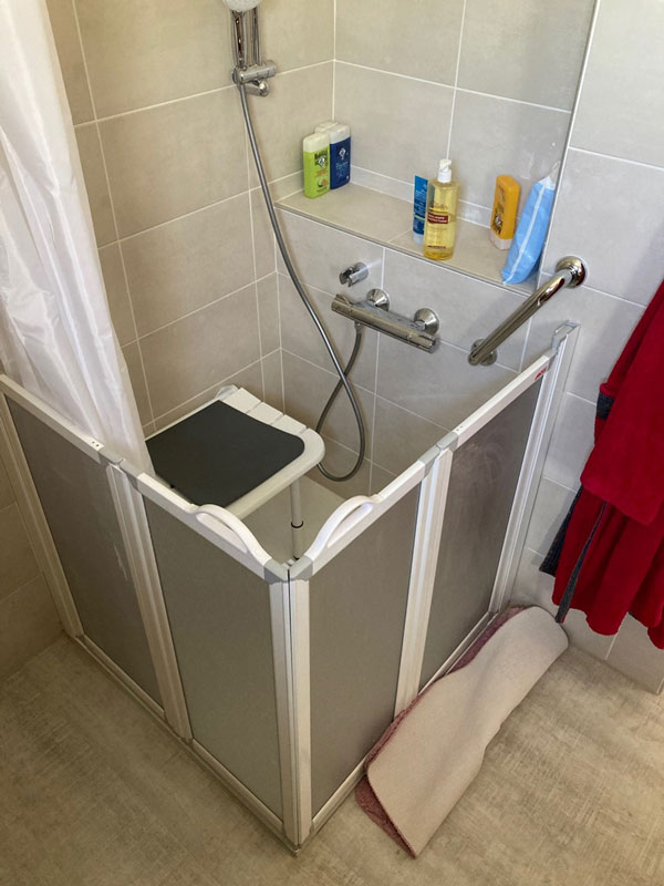 Création d’une douche à l’italienne avec paroi mi-hauteur pour accès à l’aide à la toilette. Siège de douche escamotable.